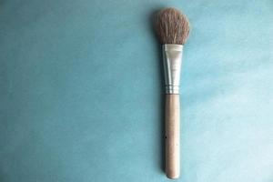 Beautiful soft brush for make-up of natural lint for the guidance of beauty and applying tonal framework with a wooden pen and copy space on a blue background photo