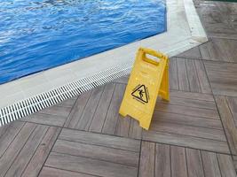 suelo mojado con letrero amarillo cerca de la piscina con agua para nadar y relajarse en un hotel en un cálido complejo tropical del este del país foto