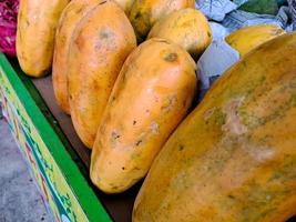 bunch of sweet orange papaya fruit. several big sweet papaya fruit put on wooden table on natural background for sale in fruit shop photo