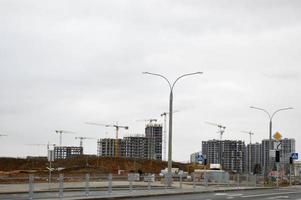 Construction of a new microdistrict with high houses, new buildings with developed infrastructure with the help of large industrial cranes and professional construction equipment in a big city photo