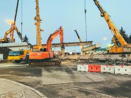 construction of a broken bridge on a busy road. the crane carries large concrete blocks. repair of the bridge behind the barrier for the passage of people photo