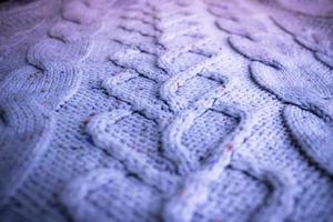 Beautiful texture of a soft warm natural sweater with a knitted pattern of threads. The background photo