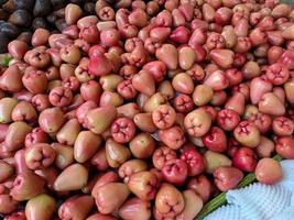 manojo de guayaba de agua roja dulce varias frutas colocadas sobre una mesa de madera sobre fondo natural a la venta en una frutería foto