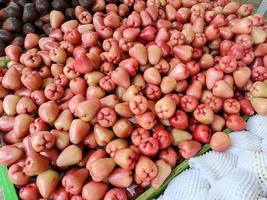 manojo de guayaba de agua roja dulce varias frutas colocadas sobre una mesa de madera sobre fondo natural a la venta en una frutería foto