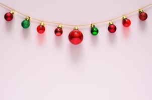 Colorful Christmas baubles ornament hanging on top with pink background. Minimal holiday concept. photo