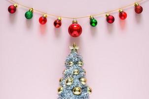 Christmas tree with colorful baubles ornament on top with pink background. Minimal holiday concept. photo