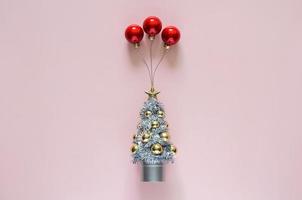 Christmas tree with red baubles ornament set as ballon on top with pink background. Minimal holiday concept. photo