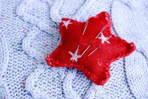 Beautiful texture of a soft warm natural sweater, a fabric with a knitted pattern and a needle pad for sewing. Flat lay. The background photo