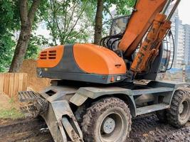 equipos de construcción para la construcción de casas. camión volquete naranja brillante para levantar pesas hasta la cima. equipo sobre grandes ruedas de goma para la construcción foto