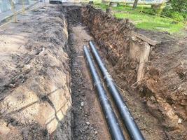 laying of underground communications for residential buildings. black plumbing pipes made of durable and reliable material are buried deep in an earthen ditch photo