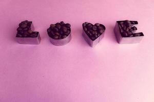 Beautiful texture with the word love for valentine's day inscription made from roasted selected brown natural aromatic Arabica coffee beans, robusta Copy space, flat lay, pink purple background photo