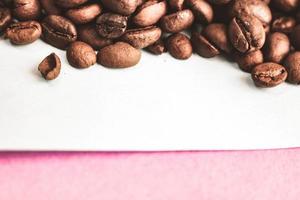 Beautiful texture of freshly roasted selected delicious rich brown natural fragrant coffee tree grains, Arabica coffee beans, Robusta. Flat lay and copy space on pink blue background photo