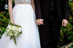 la novia tiene un ramo de novia en sus manos, flores para el día de la boda. foto