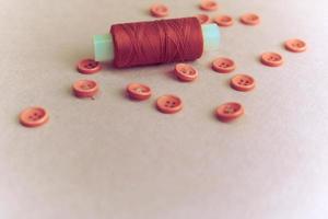 Beautiful texture with many round pink buttons for sewing, needlework and a coil of thread. Copy space. Flat lay. Pink, purple background photo