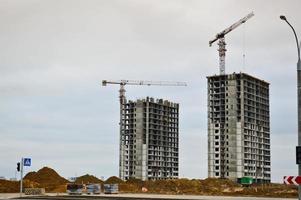 Construction of a new microdistrict with high houses, new buildings with developed infrastructure with the help of large industrial cranes and professional construction equipment in a big city photo