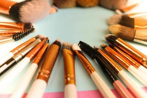 A frame from a set of beautiful different soft makeup brushes from natural lint for targeting beauty and applying a tonal foundation in a stand and copy space on a blue background photo