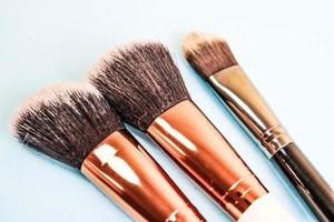 A set of beautiful different soft brushes for make-up from natural nap for beauty targeting and applying a tonal foundation in a stand and copy space on a blue background photo