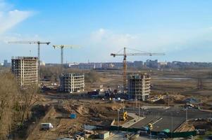 vista superior de un gran sitio de construcción con grúas y edificios que albergan rascacielos monolíticos de hormigón de varios pisos de la gran ciudad de la metrópolis foto