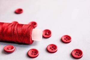 hermosa textura con muchos botones rojos redondos para coser, costura y una bobina de hilo. copie el espacio endecha plana Fondo blanco foto