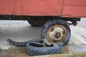 A large black rusty rubber wheel with a torn worn out broken bad old full of tires insecure tire photo