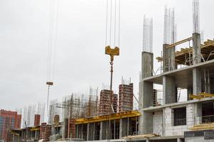 The process of construction and repair of a new modern cement concrete stone pannel monolithic frame-block building of a house with iron reinforcement at an industrial construction site photo