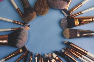 A frame from a set of beautiful different soft makeup brushes from natural lint for targeting beauty and applying a tonal foundation in a stand and copy space on a blue background photo