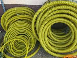 Many large coils of yellow thick plastic hoses of large diameter for pumping liquids in an industrial warehouse photo