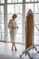 Beautiful woman in lace robe looks at her reflection in mirror while standing photo