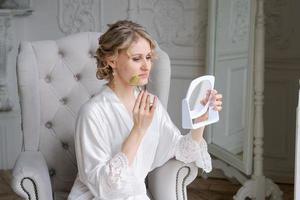 Beautiful woman in silk robe using jade face roller with natural stones doing photo