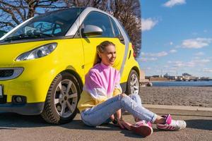 mujer feliz cerca de un auto amarillo en la ciudad foto