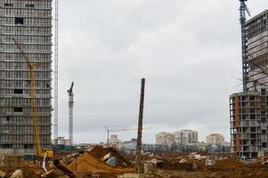 construcción de grandes casas monolíticas modernas, edificios que utilizan equipos de construcción industrial y grandes grúas altas. construcción del edificio en el nuevo micro distrito de la ciudad foto