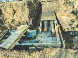 laying of underground communications for residential buildings. black plumbing pipes are buried underground on a wooden foundation to protect communications from pollution photo