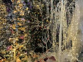 Festive green Christmas tree decorated with gold and red toys balls and bows with soft focus in evening and beautiful dark blurred defocused sparkling background with golden highlights, copy space photo