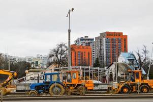 Many powerful industrial heavy specialized construction equipment of tractor excavators and bulldozers make road repairs during the construction of a new micro-district in a big city photo