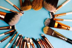 A frame from a set of beautiful different soft makeup brushes from natural lint for targeting beauty and applying a tonal foundation in a stand and copy space on a blue background photo