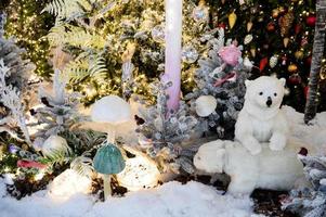 shop window decoration, shopping center decor. artificial white spruce with garlands. next to them are two polar bear cubs. artificial porcini mushrooms in the forest photo