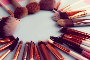 A frame from a set of beautiful different soft makeup brushes from natural lint for targeting beauty and applying a tonal foundation in a stand and copy space on a blue background photo