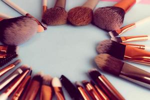 A frame from a set of beautiful different soft makeup brushes from natural lint for targeting beauty and applying a tonal foundation in a stand and copy space on a blue background photo