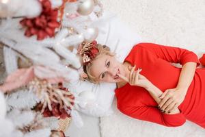 Young beautiful woman lie on floor in Christmas decoration at home under photo