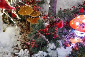 decoración navideña para un centro comercial. lindas setas amanita con luces adentro. junto a ellos hay pájaros rojos hechos de materiales artificiales. una corona navideña está hecha de serbal foto