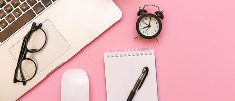 White notepad with office and personal accessories, black alarm clock and photo
