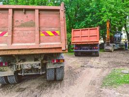 un camión con carrocería para el transporte de cosas pesadas. adhesivo resistente en la parte posterior del cuerpo. al lado del camión hay otro auto con carrocería foto