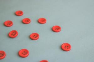 Beautiful texture with many round red buttons for sewing, needlework. Copy space. Flat lay. Blue background photo