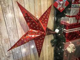 grandes y lindas estrellas rojas navideñas, navidad, decoración de año nuevo contra el fondo de gerlyand brillante sobre tablas verticales de madera con costuras foto