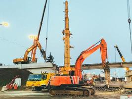 construction of a broken bridge on a busy road. the chipper makes a hole in the asphalt to replace it. repair of the bridge behind the barrier for the passage of people photo