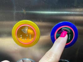 A woman's manicured finger on her hand presses a button in a modern beautiful elevator in a high-rise building photo
