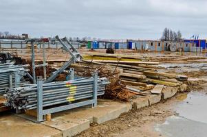 muchos materiales de construcción con piezas de repuesto metálicas, palos, vigas, tuberías en un almacén de obra al aire libre foto