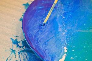 The process of creating a home-made trendy abstract modern pattern painted with a brush of acrylic blue multi-colored resin on a round wooden board photo