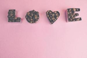 Beautiful texture with the word love for valentine's day inscription made from roasted selected brown natural aromatic Arabica coffee beans, robusta Copy space, flat lay, pink purple background photo