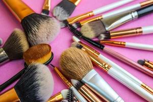 A set of beautiful different soft brushes for make-up from natural nap for beauty targeting and applying a tonal foundation in a stand and copy space on a pink, purple background photo